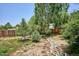 Well-manicured backyard featuring a stone path, lush landscaping, mature trees, and wood fencing at 800 Park View Pl, Castle Rock, CO 80104