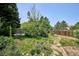 Spacious backyard featuring lush greenery, mature trees, stone pathway, and a wood fence at 800 Park View Pl, Castle Rock, CO 80104