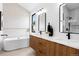 Spa-like bathroom featuring a sleek soaking tub, wood vanity, dual mirrors and a glass shower at 2478 S Cherokee St, Denver, CO 80223