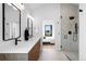 Modern bathroom leading to bedroom with glass shower, dual mirrors and sinks, wood vanity at 2478 S Cherokee St, Denver, CO 80223