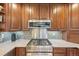 Stainless steel gas cooktop and microwave in a rich wood cabinet kitchen at 3257 S Pontiac St, Denver, CO 80224