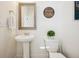 Charming half bathroom featuring pedestal sink, decorative mirror, and a modern toilet with green plant decor at 1015 Auburn Dr, Erie, CO 80516