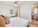 Bright bedroom featuring a ceiling fan, light hardwood floors, and a doorway to the bathroom at 13640 W Center Dr, Lakewood, CO 80228