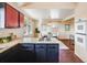 Open kitchen featuring an island cooktop, stylish cabinets, and a view into the dining area at 13640 W Center Dr, Lakewood, CO 80228