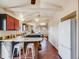 Charming kitchen with an island, red upper cabinets, white appliances, and exposed ceiling beams at 13640 W Center Dr, Lakewood, CO 80228