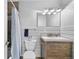 Bright bathroom featuring a wood vanity, white fixtures, and shower with a blue curtain at 6864 Balsam St, Arvada, CO 80004