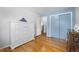 Light-filled bedroom with hardwood floors, white dresser, blue accent wall, and closet at 6864 Balsam St, Arvada, CO 80004