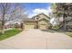 Rear view of a home featuring a three-car garage, a basketball hoop, and a lush green lawn at 25 Summit Ash, Littleton, CO 80127