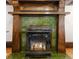 Close-up of a green tile fireplace with a detailed wood mantel and black stove at 1220 S Vine St, Denver, CO 80210