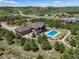 Aerial view of a sprawling estate with pool, fire pit, and well-manicured grounds surrounded by lush greenery at 1505 Castlecombe Ln, Monument, CO 80132