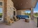 Inviting back porch with stone accents, comfortable seating, and a barrel table overlooking the yard at 1505 Castlecombe Ln, Monument, CO 80132