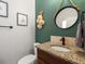 Stylish powder room with a granite-topped vanity, bronze fixtures, and a round decorative mirror at 1505 Castlecombe Ln, Monument, CO 80132
