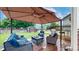 Backyard featuring a large canopy-covered seating area, wooden deck, and lush green grass at 12201 N Holly Way, Brighton, CO 80602