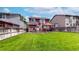 Spacious backyard with lush green lawn, a deck with outdoor seating, and privacy fence at 12201 N Holly Way, Brighton, CO 80602