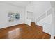 Bright, empty living room featuring beautiful hardwood floors, white walls, and a staircase with white railings at 9515 Bexley Dr, Highlands Ranch, CO 80126