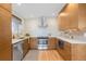Modern kitchen with stainless steel appliances, white backsplash, wooden cabinets, and a window over the sink at 3035 E Maplewood Ave, Centennial, CO 80121