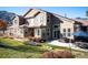 Charming home's outdoor patio area with a grill, table, and umbrella, overlooking the well-maintained backyard at 16226 River Haven Way, Morrison, CO 80465