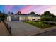 Charming single-story home at dusk with a well-manicured lawn, a long driveway, and an attached garage at 13010 W 6Th Pl, Golden, CO 80401