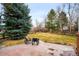 Spacious backyard with lush lawn, mature trees, a patio with fire pit, and a wooden fence at 6071 Russell Ln, Arvada, CO 80403