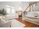 Sunlit living room with high ceilings, hardwood floors, comfortable seating, and a view of the staircase at 6071 Russell Ln, Arvada, CO 80403