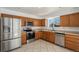 Well-lit kitchen featuring stainless steel appliances, wood cabinets, tile flooring, and a window above the sink at 14936 E Arizona Pl, Aurora, CO 80012