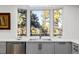 Bright kitchen sink with stainless steel appliances, gray cabinetry and large window overlooking trees at 37 Wagner Cir, Boulder, CO 80304