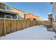 Snowy backyard with wooden fence and neighboring houses at 677 Brookwood Dr, Lafayette, CO 80026