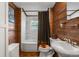 Rustic bathroom features wood paneled walls, shower over tub with curtains, sink, and toilet at 2862 S Grant St, Englewood, CO 80113