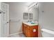 Bright bathroom featuring a wood vanity, a sink, a large mirror with Hollywood lights, and a toilet at 5705 N Genoa Way # 206, Aurora, CO 80019