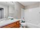 Bathroom features a wooden vanity, a sink and faucet, toilet, and tub-shower combination with white tiling at 5705 N Genoa Way # 206, Aurora, CO 80019
