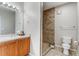 This bathroom features a wooden vanity, a shower with tan tiling, and a toilet at 5705 N Genoa Way # 206, Aurora, CO 80019