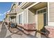 Townhouse entry with brick facade, small porch, and olive green door at 16058 E Geddes Ln # 26, Aurora, CO 80016