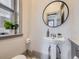 Stylish bathroom showcasing a pedestal sink, round mirror, and natural light, creating a serene and inviting space at 1475 Saint Paul St, Denver, CO 80206