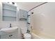 Bathroom with light blue vanity, built-in shelving, and a shower-tub combo at 9844 Fairwood St, Littleton, CO 80125