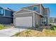View of a two-car garage and front yard with newly installed sod at 28630 E 8Th St, Watkins, CO 80137