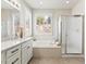 Bathroom featuring a soaking tub under a window with shutters and a glass enclosed shower at 23327 E Ottawa Dr, Aurora, CO 80016