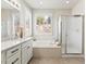 Well-lit bathroom with dual windows, a soaking tub, a vanity, and a glass door shower at 23327 E Ottawa Dr, Aurora, CO 80016