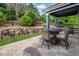 Relaxing outdoor covered patio with a stone surface, complemented by mature landscaping and stone retaining wall at 23327 E Ottawa Dr, Aurora, CO 80016