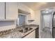 Kitchen featuring granite countertops, stainless steel sink, and white cabinetry at 9867 E Peakview Ave # E1, Englewood, CO 80111