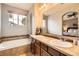 Bathroom featuring a soaking tub, double vanity, and ample natural light at 15362 W 66Th Ave # D, Arvada, CO 80007