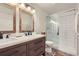 Bathroom with a wood vanity, double sinks, and a glass-enclosed shower with white subway tiles at 2572 Iola St, Aurora, CO 80010