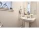 Charming powder room with pedestal sink, decorative mirror, and window, showcasing elegant simplicity at 2572 Iola St, Aurora, CO 80010