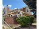 Inviting two-story home featuring a brick retaining wall, white railing, and lush landscaping at 2136 S Scranton Way, Aurora, CO 80014