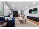 Spacious living room with hardwood floors, blue sofa, mounted TV, and easy access to the staircase at 7724 S Lafayette Ct, Centennial, CO 80122