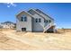 New construction home with gray siding, white trim, basement access, and a wooden back deck with stairs at 39628 Yorktown Ter, Elizabeth, CO 80107