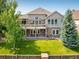 A two-story home showcasing a lush backyard, a stone patio, and a charming balcony on the second story at 13943 W 87Th Ln, Arvada, CO 80005