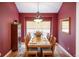 Formal dining room featuring a large wooden table, decorative chandelier, and red walls at 13943 W 87Th Ln, Arvada, CO 80005
