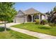 Single-story home featuring a well-kept lawn, lush landscaping, a three-car garage, and charming stone accents at 13943 W 87Th Ln, Arvada, CO 80005