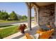 Cozy front porch of a home, featuring stone pillars, a comfortable seating area, and a view of the street at 13943 W 87Th Ln, Arvada, CO 80005