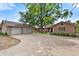 Expansive driveway leads to a three car garage and brick home, surrounded by mature trees at 6307 S Gallup St, Littleton, CO 80120
